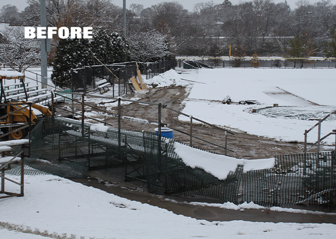 Snow covers bleachers and a muddy, fenced-off area at a sports field. Equipment and construction barriers are visible, with trees and a partially frozen field in the background. The word BEFORE is overlaid.